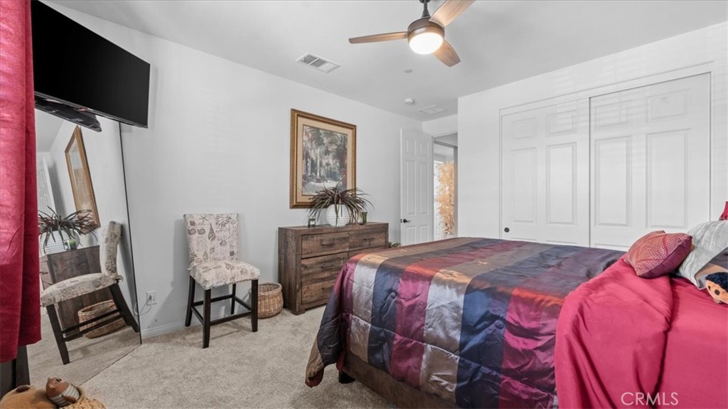 35580 Roxy Road Beaumont, CA 92223 - Photo 23 of 39 a bedroom with a bed a flat screen tv and a chandelier