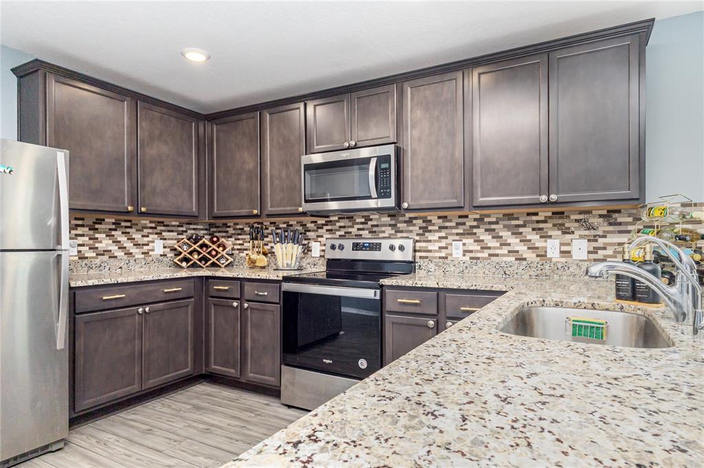 1760 Canaan Loop Dundee, FL 33838 - Photo 11 of 25 a kitchen with stainless steel appliances granite countertop a sink stove and refrigerator