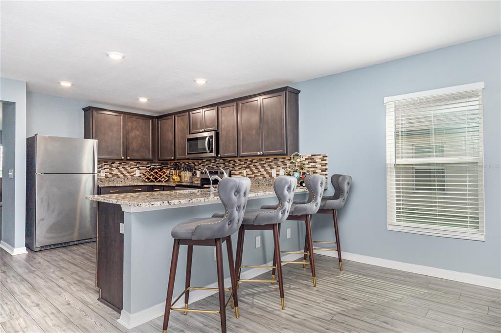 1760 Canaan Loop Dundee, FL 33838 - Photo 8 of 25 a kitchen with granite countertop a refrigerator a stove a sink and white cabinets with wooden floor
