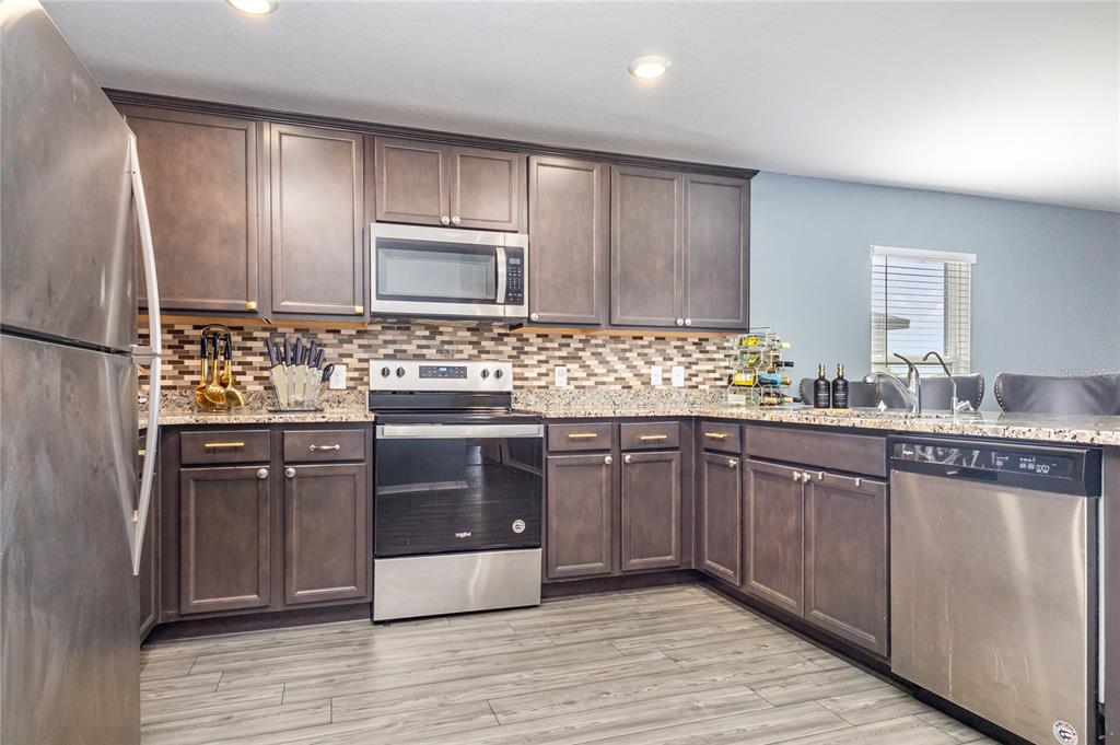 1760 Canaan Loop Dundee, FL 33838 - Photo 10 of 25 a kitchen with stainless steel appliances granite countertop wooden cabinets a refrigerator and a sink