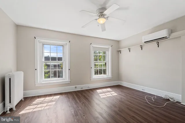 an empty room with wooden floor fan and windows