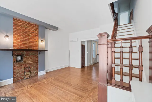 a view of an empty room with wooden floor and a fireplace