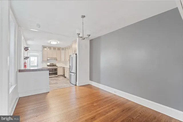 a view of a hallway with wooden floor and a kitchen