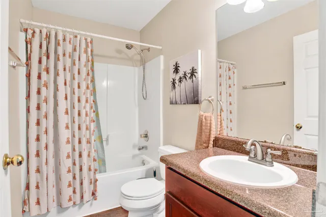 a bathroom with a granite countertop sink toilet a mirror a shower curtain and a sink