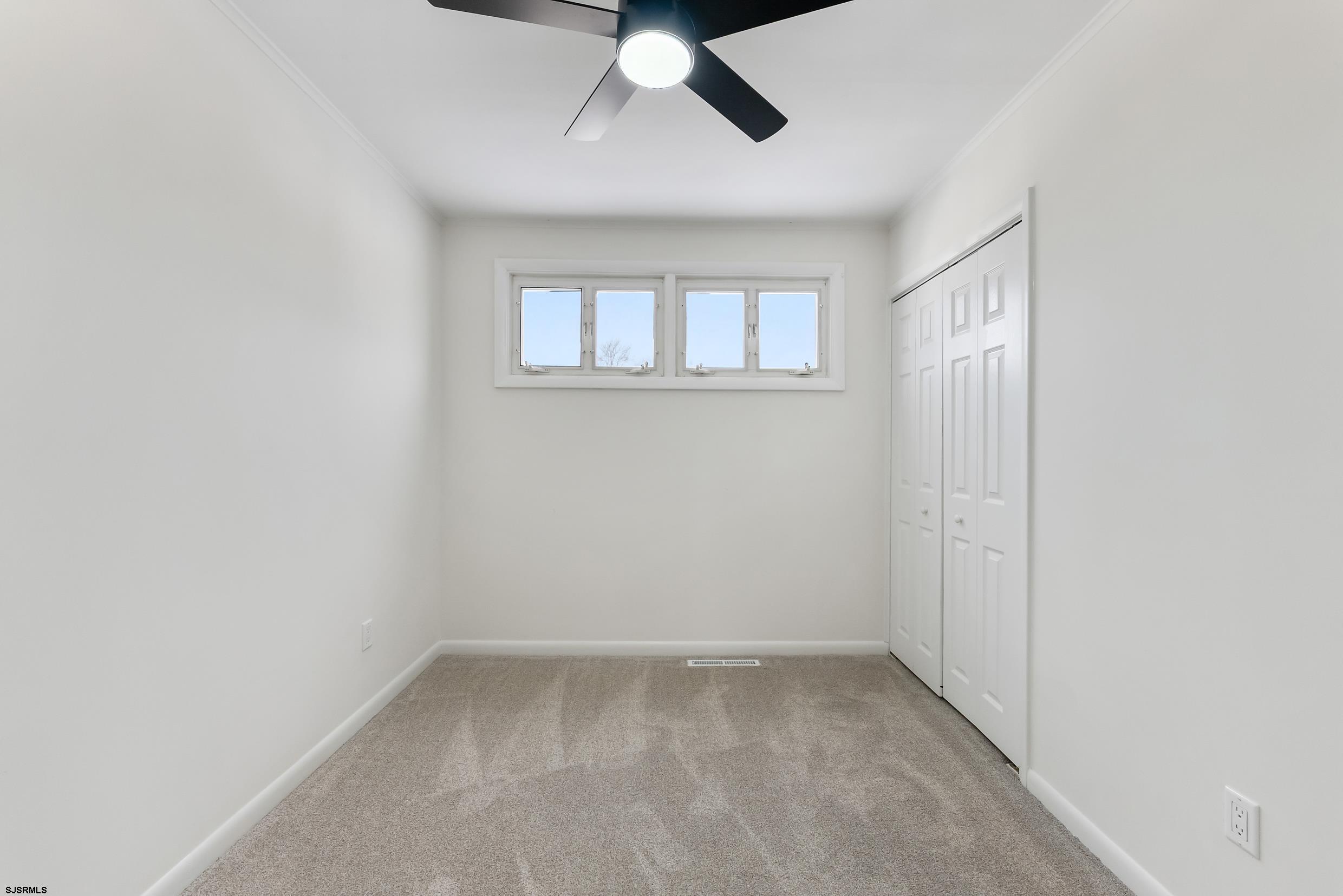 1805 Zion Road Northfield, NJ 08225 - Photo 11 of 25 an empty room with a chandelier fan and windows