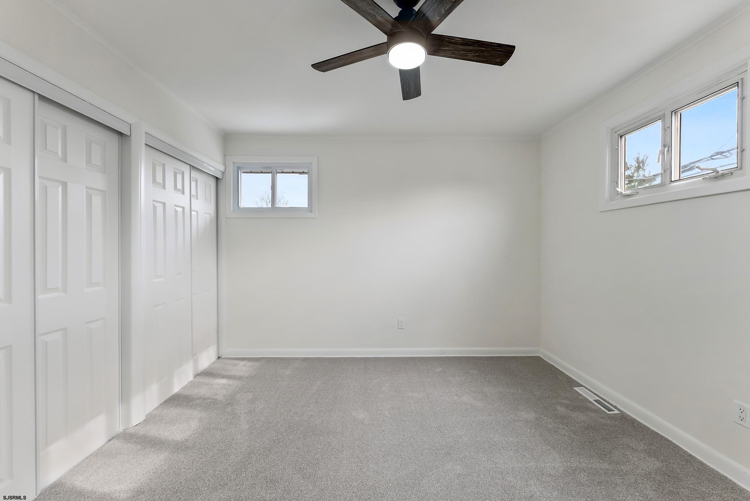 1805 Zion Road Northfield, NJ 08225 - Photo 10 of 25 an empty room with a ceiling fan and windows