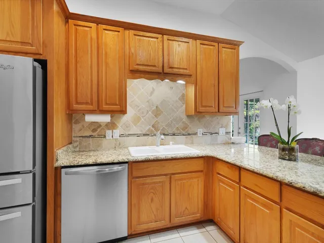 a kitchen with stainless steel appliances granite countertop a sink refrigerator and cabinets
