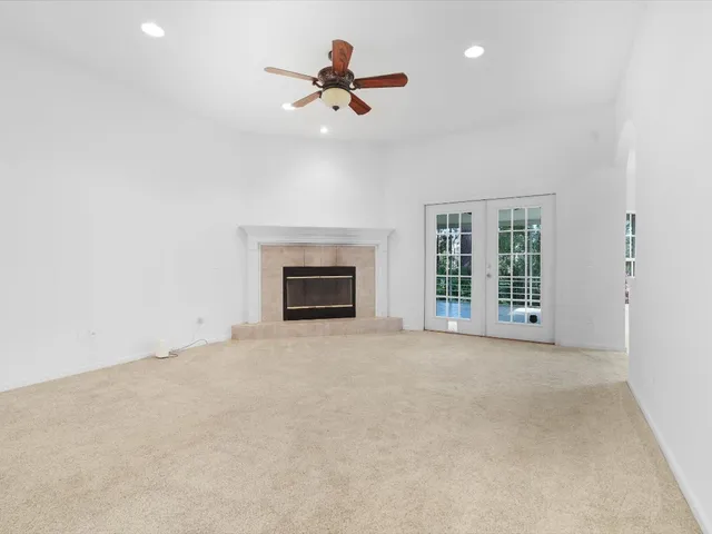 an empty room with ceiling fan and windows