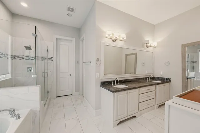 a spacious bathroom with a granite countertop sink a mirror and a shower