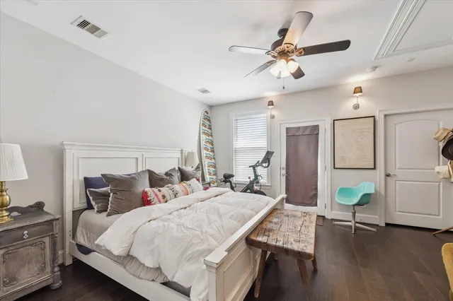 a bedroom with a bed a desk and chair with wooden floor