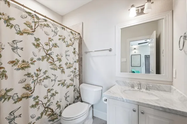 a bathroom with a granite countertop sink a toilet and a mirror