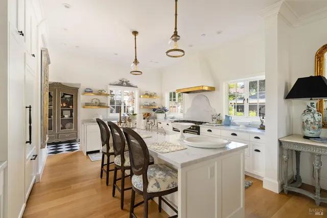 a kitchen with stainless steel appliances kitchen island granite countertop a table chairs in it and wooden floors
