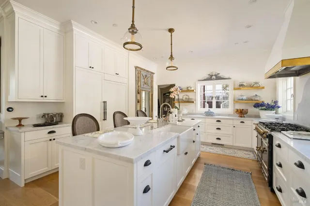 a kitchen with stainless steel appliances a stove a sink a chimney wooden floor and cabinets