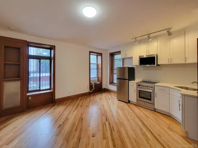 an empty room with kitchen wooden floor and windows