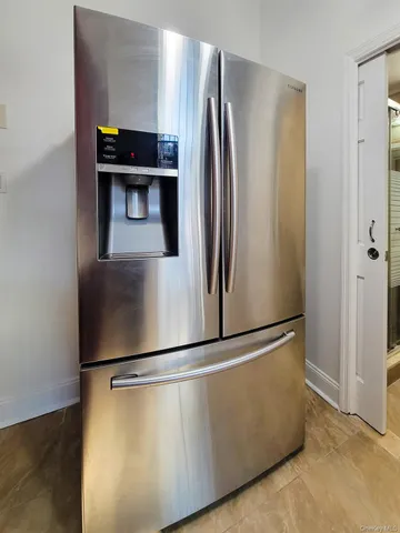 a view of a refrigerator in kitchen and an empty room