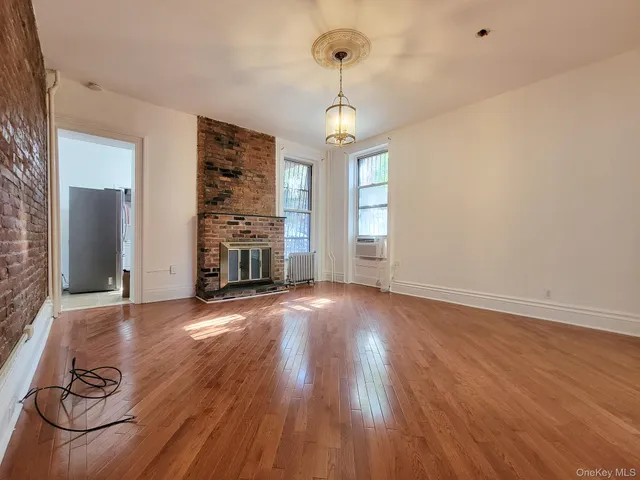 a view of empty room with wooden floor and fireplace