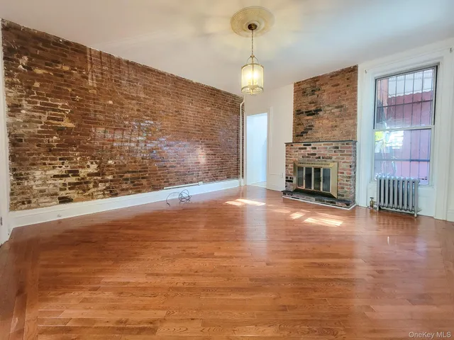 a view of empty room with wooden floor and fireplace