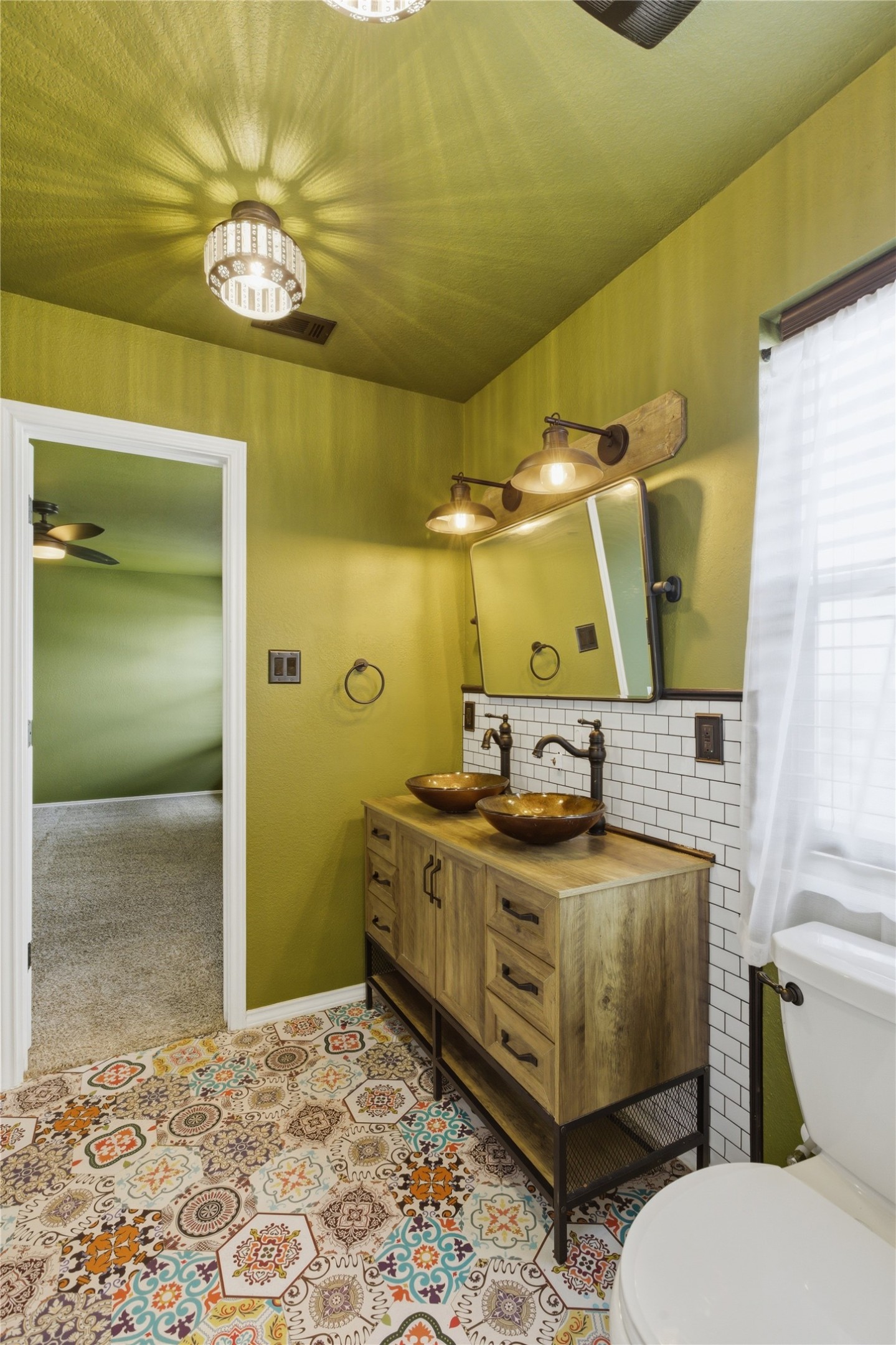 116 Night Riders Way Jarrell, TX 76537 - Photo 25 of 40 Primary bathroom featuring vibrant patterned floor tiling, a dual vessel sink vanity with wood-finish cabinetry, and subway tile backsplash