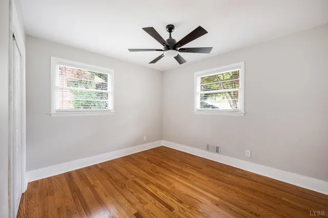 a view of a big room with wooden floor and windows