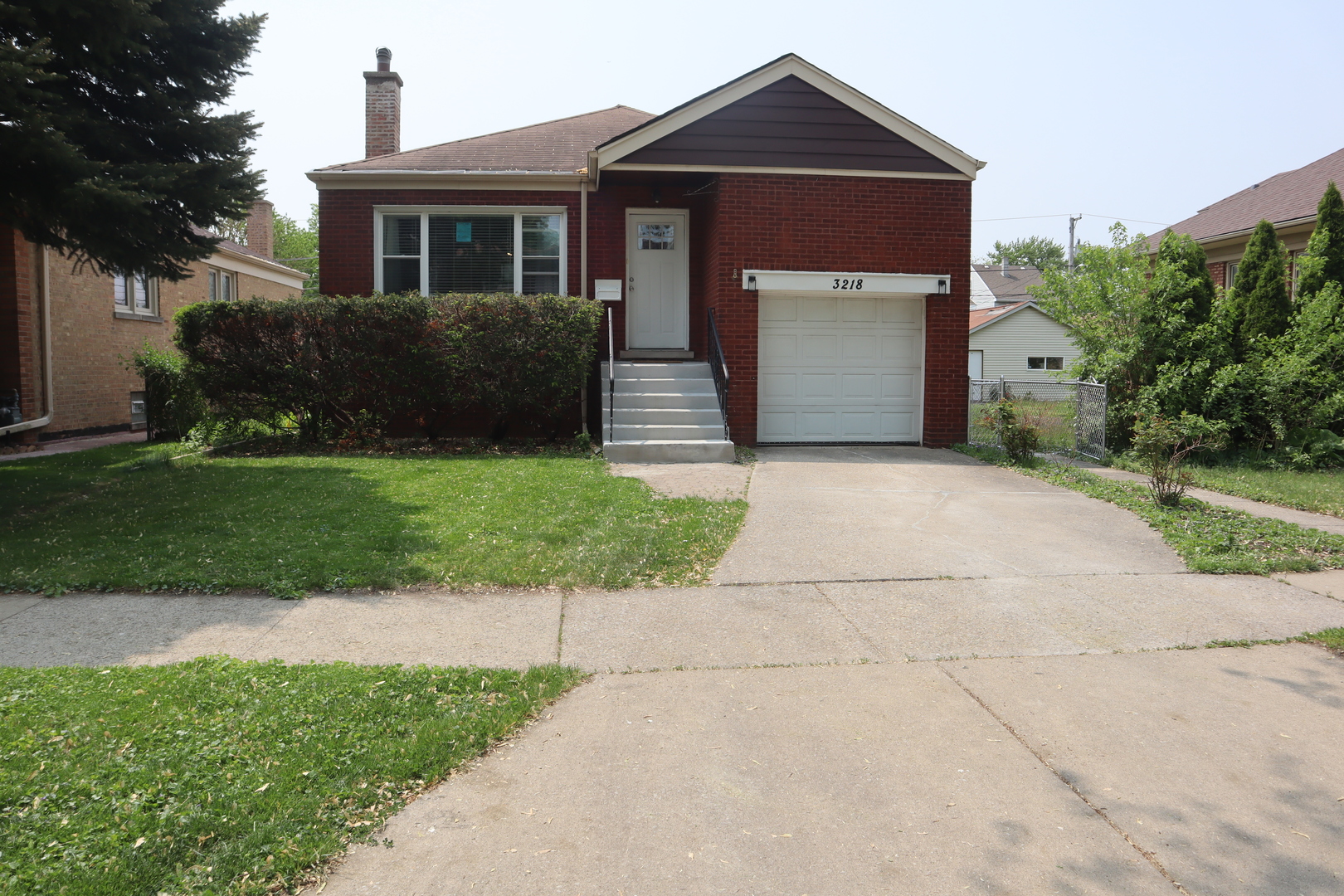 a front view of a house with a garden and trees