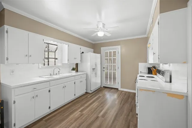 a large white kitchen with sink and cabinets