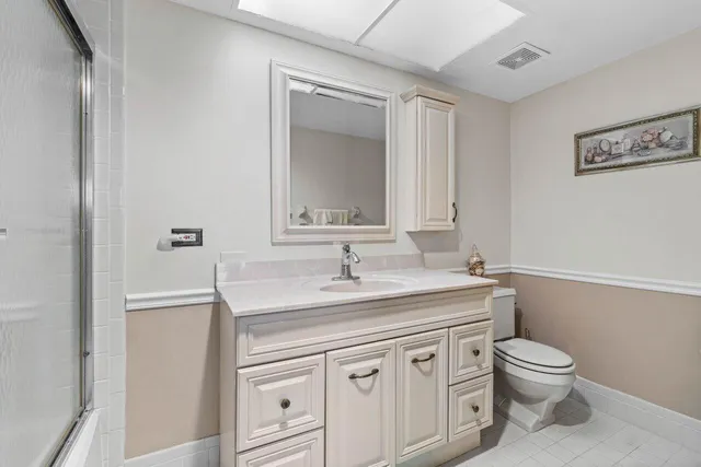 a bathroom with a granite countertop toilet sink and mirror