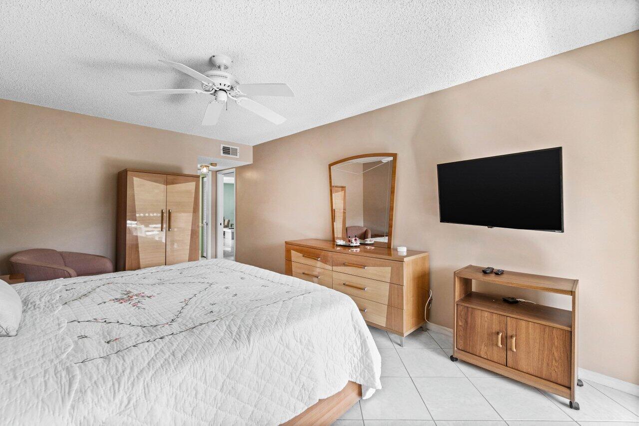 23345 Carolwood Lane, Unit 406 Boca Raton, FL 33428 - Photo 15 of 38 a bedroom with a bed and a flat screen tv