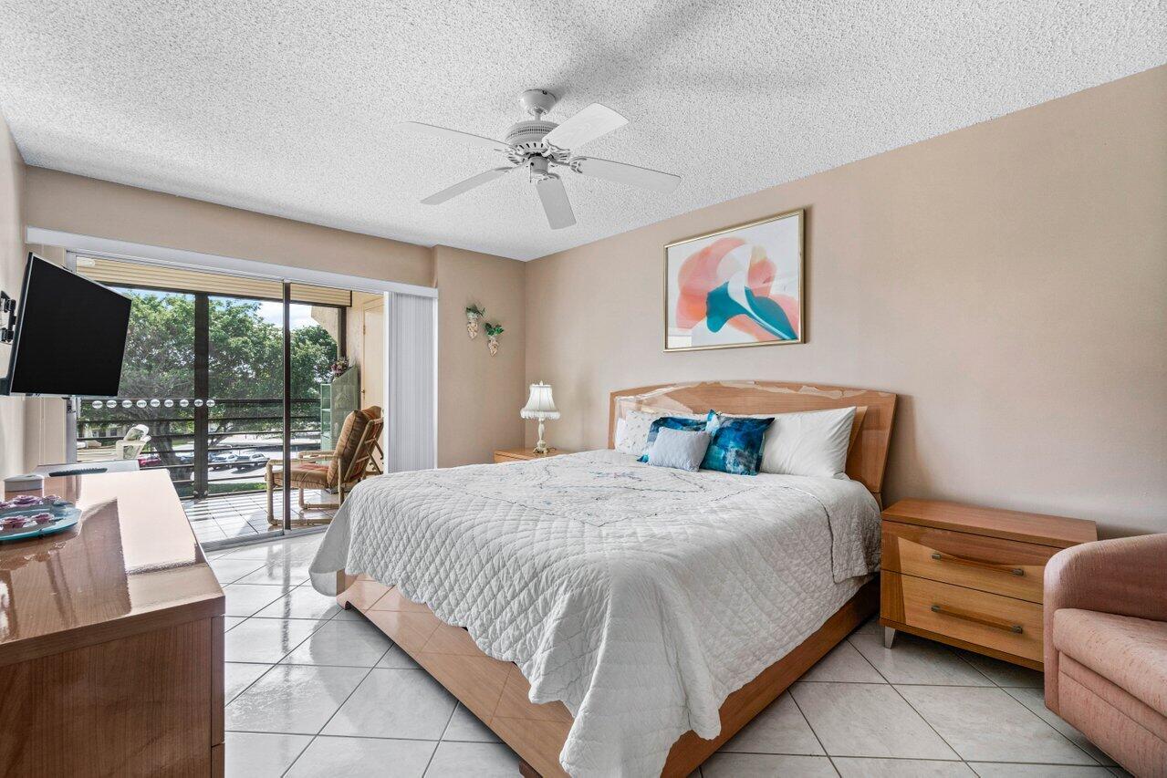 23345 Carolwood Lane, Unit 406 Boca Raton, FL 33428 - Photo 17 of 38 a bedroom with a large bed and a chandelier