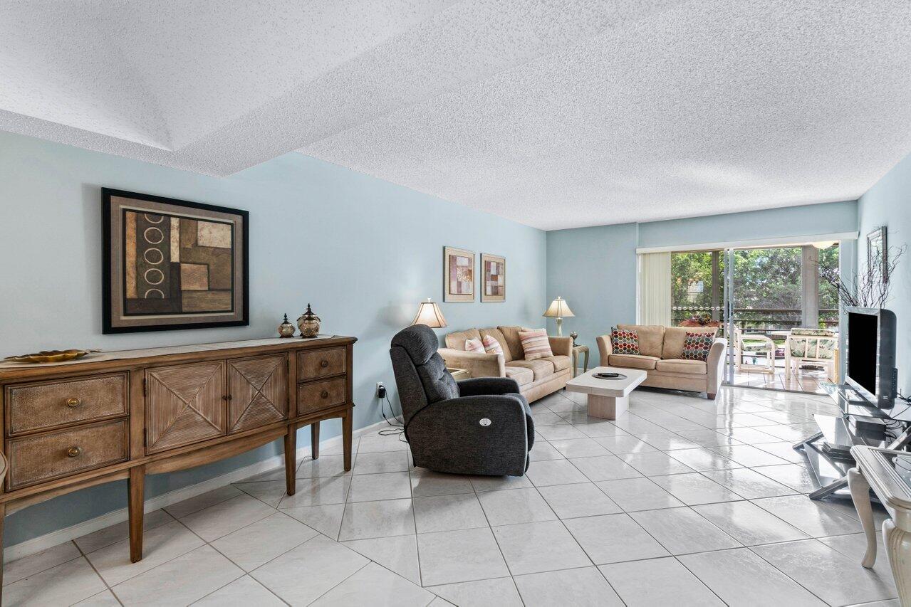 23345 Carolwood Lane, Unit 406 Boca Raton, FL 33428 - Photo 8 of 38 a living room with furniture and a flat screen tv