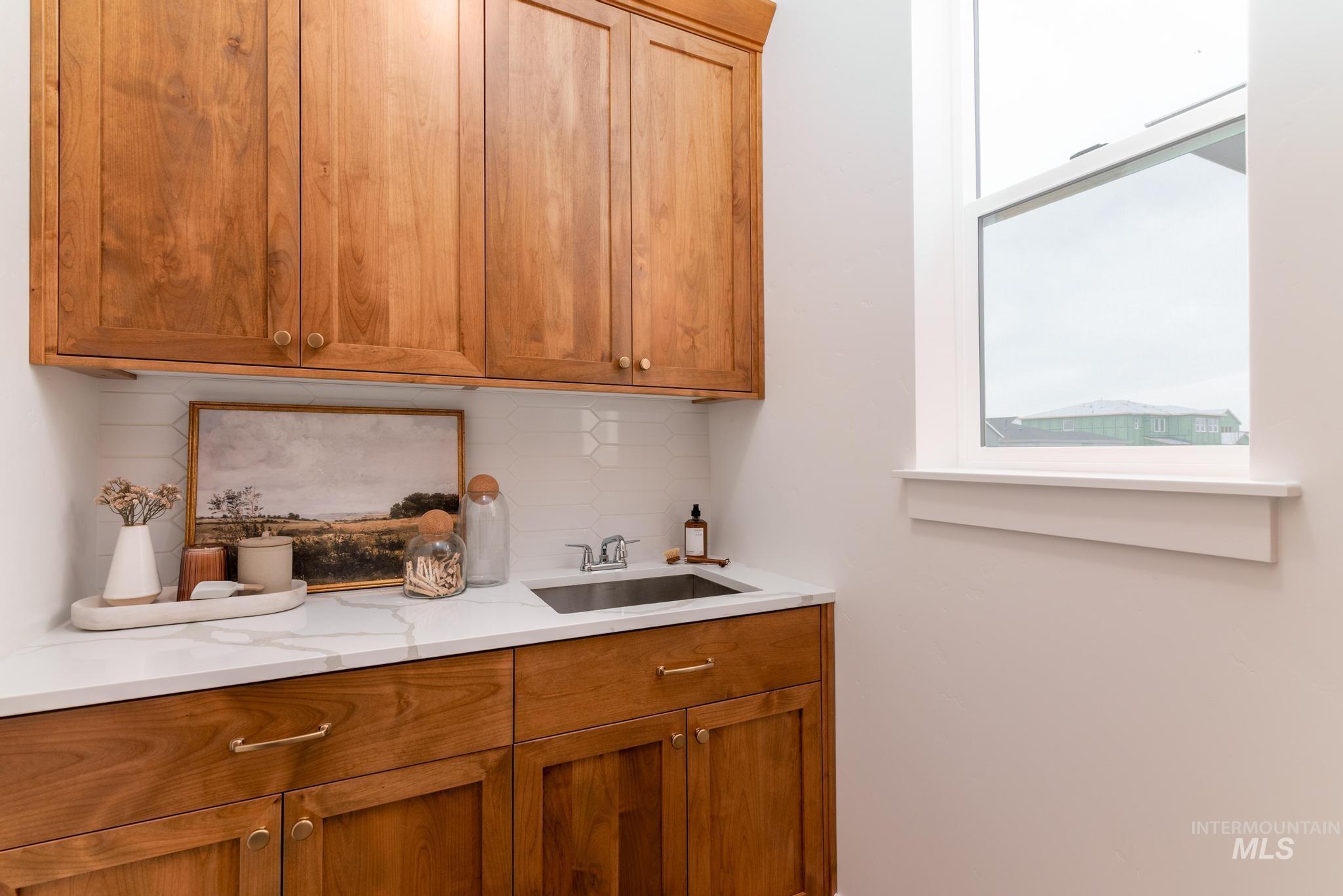 9044 West Purple Martin Street Star, ID 83669 - Photo 13 of 14 Bar area featuring wood finish cabinets, decorative backsplash, and light stone counters