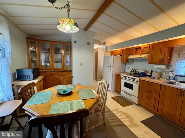 a kitchen with stainless steel appliances granite countertop a stove a sink dishwasher a dining table and chairs with wooden floor