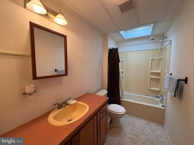 a bathroom with a granite countertop toilet sink mirror and shower