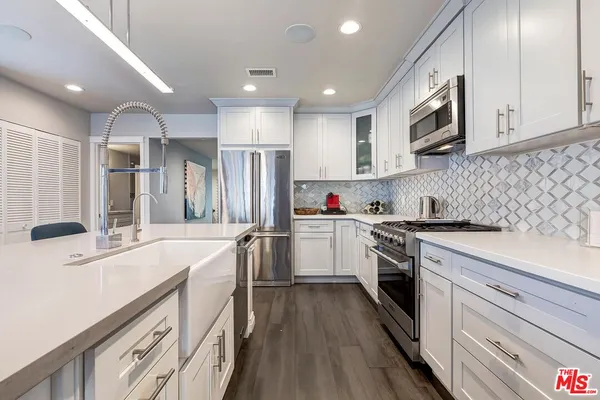 a kitchen with white cabinets sink and stainless steel appliances