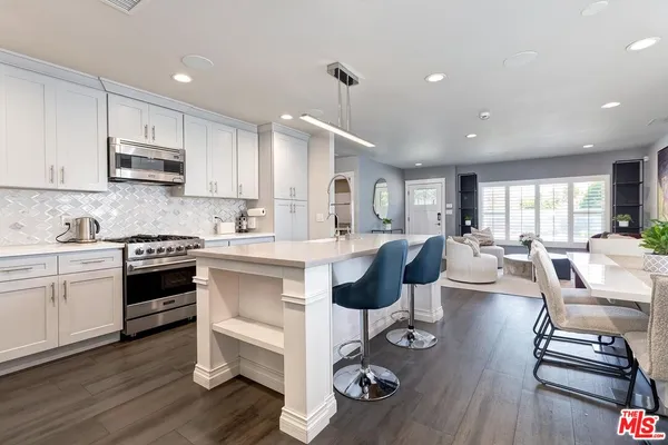 a kitchen with sink stove and white cabinets with wooden floor