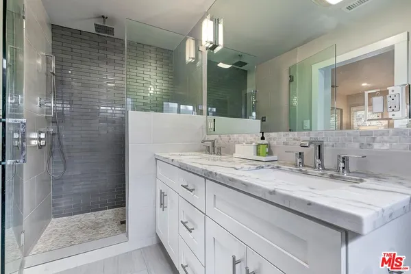 a bathroom with a granite countertop sink mirror and shower