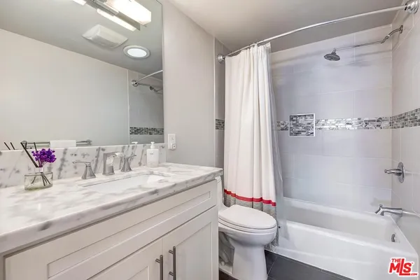 a bathroom with a granite countertop sink a toilet and shower