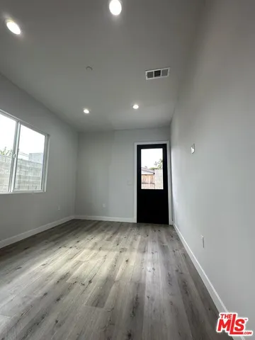 an empty room with wooden floor closet and windows