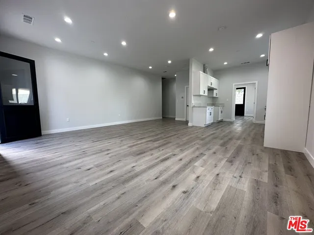 a view of a big room with wooden floor and windows