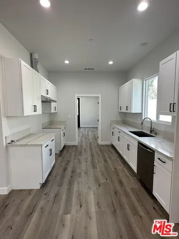 a large kitchen with a lot of counter space and wooden floor