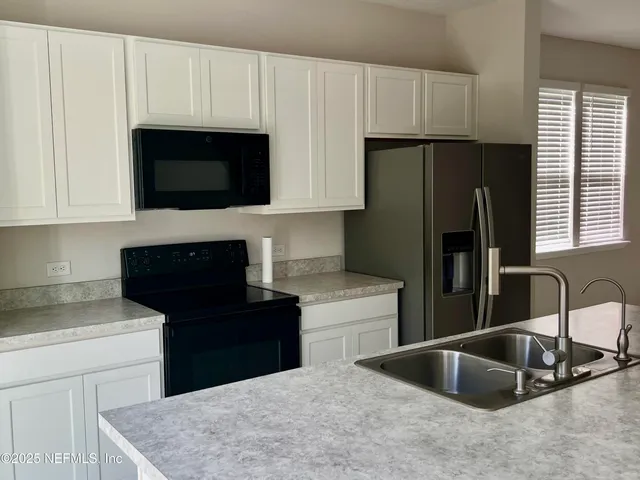 a kitchen with stainless steel appliances a stove a microwave a sink and a refrigerator