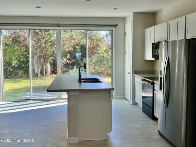 a kitchen with kitchen island a large window in it and stainless steel appliances