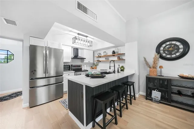 a kitchen with stainless steel appliances granite countertop a stove a refrigerator a sink a dining table and chairs with wooden floor