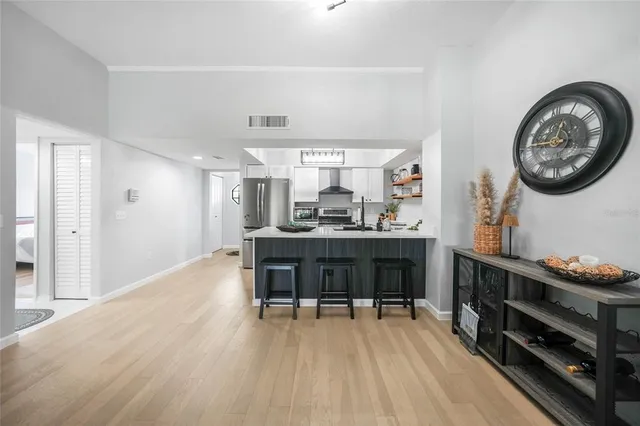 a room with a furniture a clock and a view of kitchen