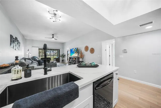 a kitchen with a sink dishwasher a stove and white cabinets with wooden floor