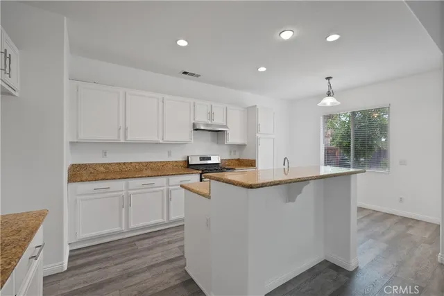 a kitchen with granite countertop a sink stove and cabinets