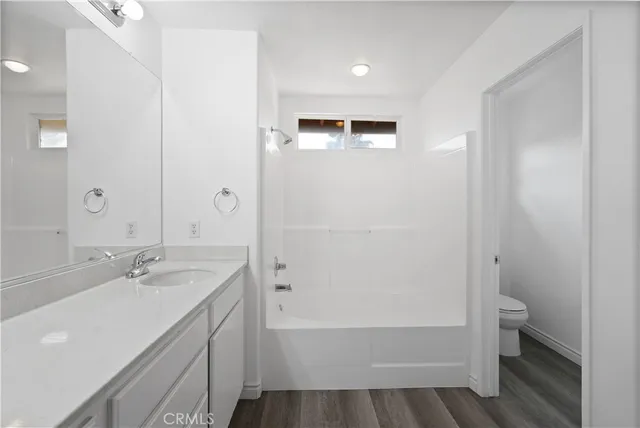 an empty room with wooden floor ceiling fan and windows