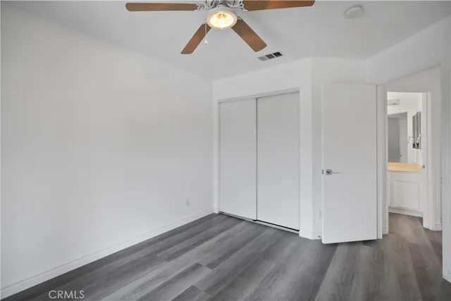 an empty room with wooden floor fan and a window