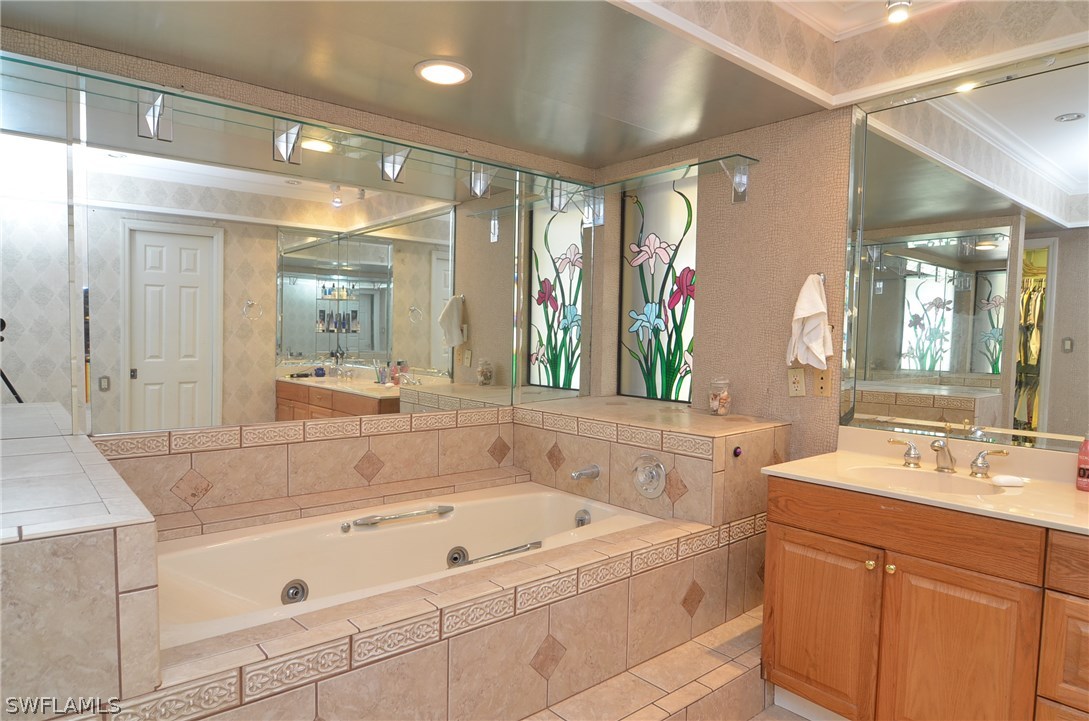 8312 Riviera Avenue Fort Myers, FL 33919 - Photo 14 of 24 a bathroom with a bathtub a mirror a double vanity sink and
