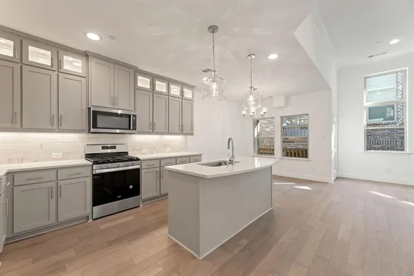 a open kitchen with stainless steel appliances granite countertop a stove oven a refrigerator a kitchen island with couches and cabinets next to a window