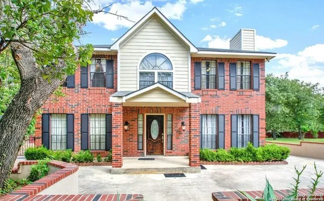 a view of a brick house with large windows and a small yard